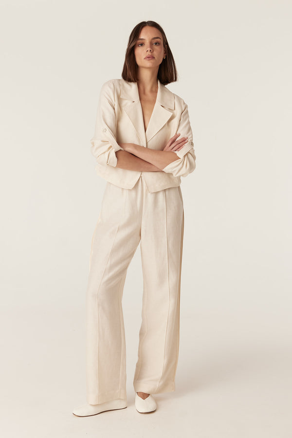 Model wearing ecru Goldie wide-leg pants and matching cropped jacket in a fluid, medium-weight fabric.