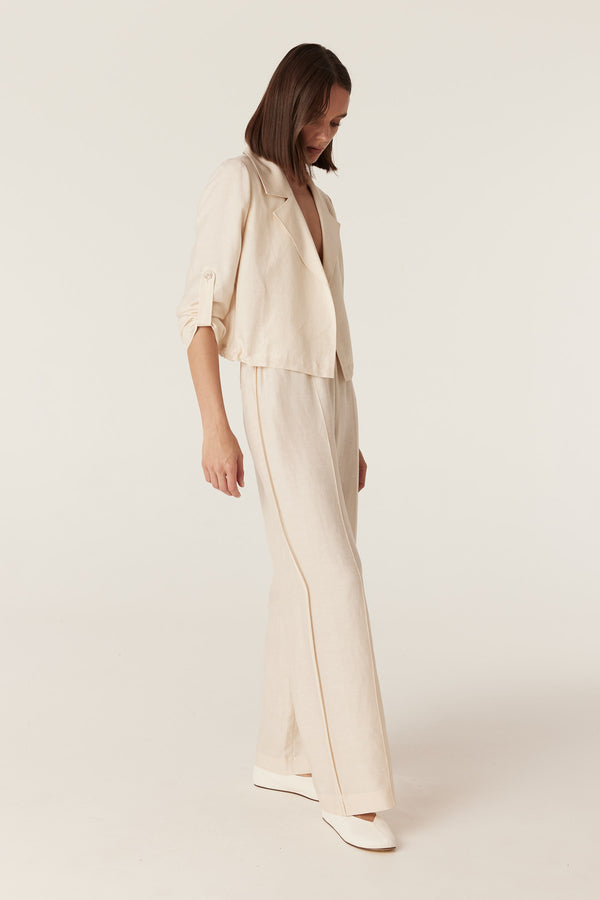Model wearing ecru wide-leg pants and a matching cropped jacket in a fluid, medium-weight fabric.