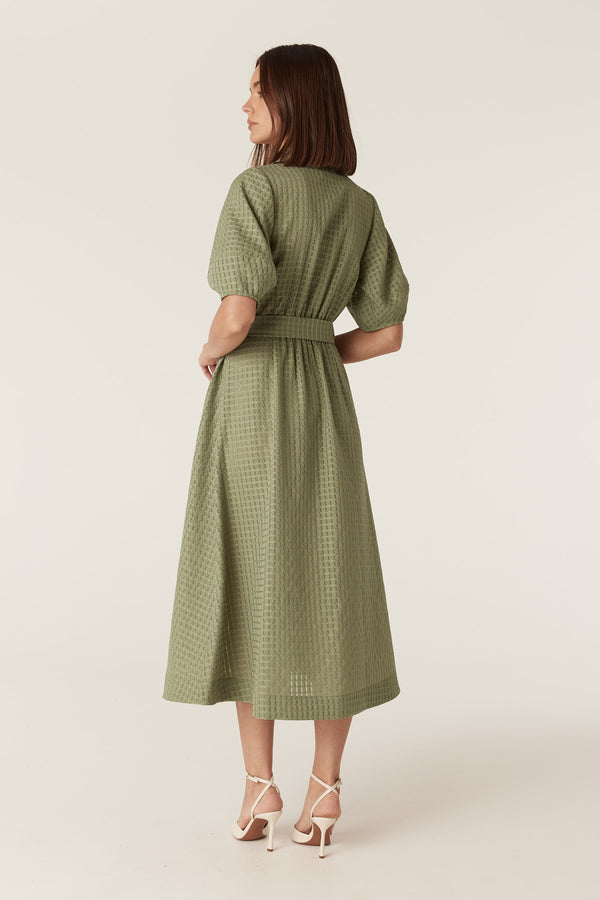 Olive midi dress in textured burnout fabric with a tie waist, puff sleeves, and a defined silhouette.
