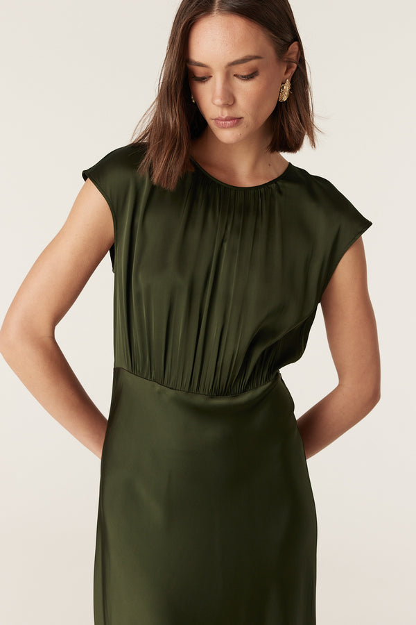 Dark green Muse dress in fluid stretch fabric with cap sleeves, a round neck, and gathered bodice detailing.