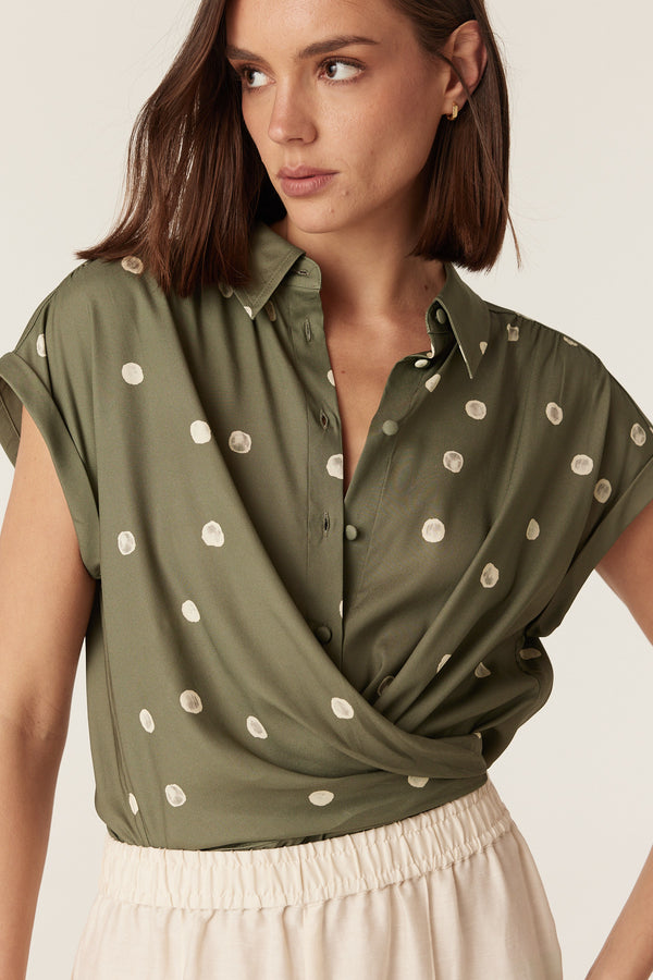 Green Muse spring blouse with white polka dots, collared neckline, and soft cap sleeves in a regular fit.