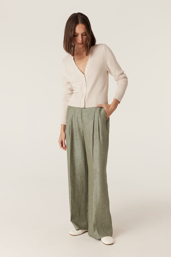 Green wide-leg Evelyn linen pants with front pleats, belt loops, and side pockets paired with a beige cardigan.