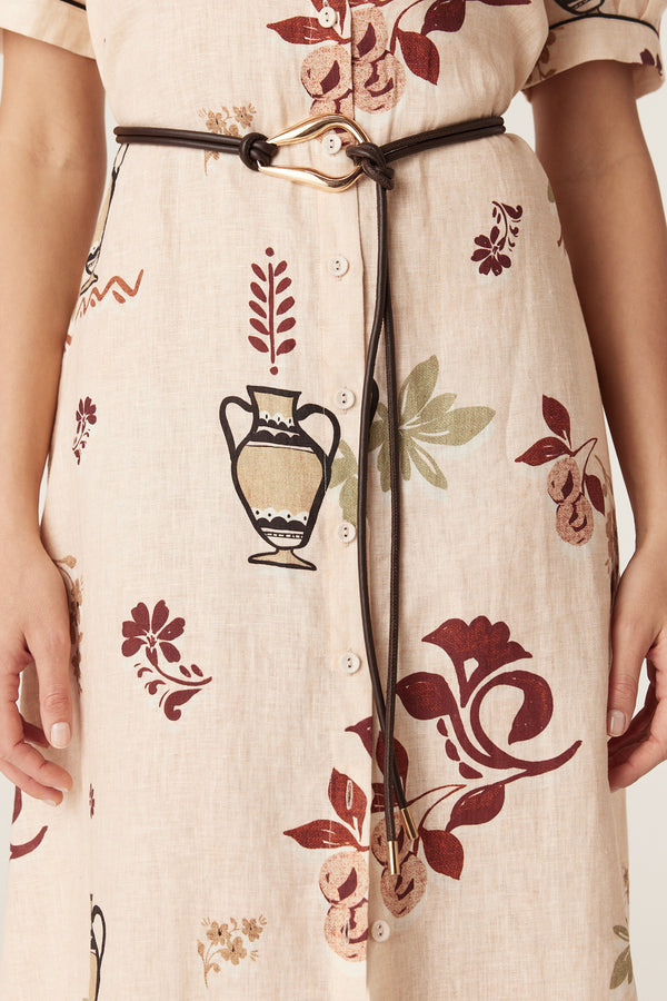 Chocolate brown Venetian leather belt with a sculptural gold-tone buckle worn over a patterned linen dress.